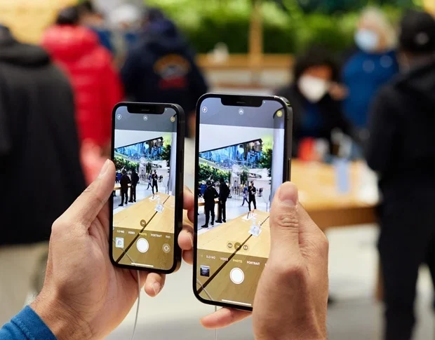 A person holding two iPhones running ios16.